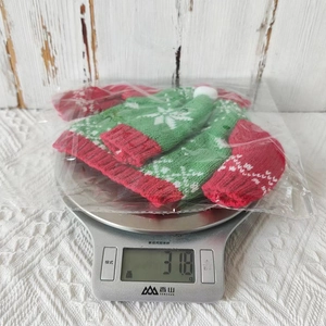 Weight measurement of a red and green knitted Christmas bottle cover showing 31.8g on a scale