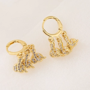 Pendientes de cisne bañados en oro de 18K con circonitas micropavé sobre fondo de tela blanca