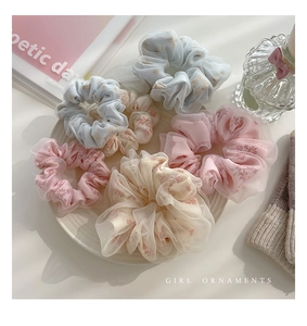 Dettaglio di elastici scrunchie in tulle floreale in colori pastello su un piatto
