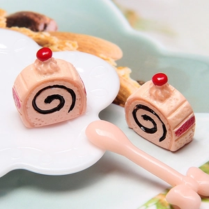 Macro view of miniature pink Swiss roll cakes with cherry topping and a small spoon