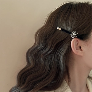 Detail of camellia flower hair clip in black velvet on elegant wavy brown hair