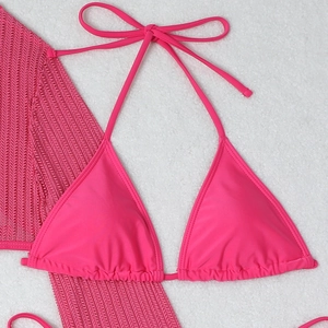Detail of rose red halter bikini set with hollow mesh cover-up on white plush surface