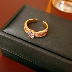 Nahaufnahme eines goldenen Rings mit lila Zirkonia und Rippendesign auf einer Schmuckbox