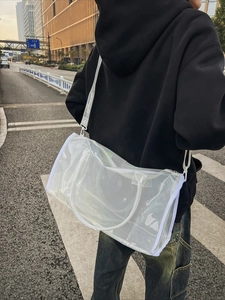 Transparent PVC beach tote with white trim shown as a shoulder bag in a street view