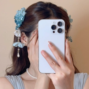 Vue détaillée de la pince à cheveux fleurs en tissu bleu et blanc avec glands perlés