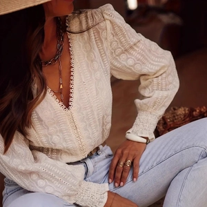 Close-up of elegant white lace shirt featuring intricate floral embroidery and V-neck detail