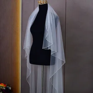 Elegant white wave bridal veil with crystal beads and a golden crown on a mannequin