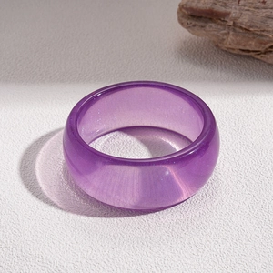 Close-up of a purple translucent resin ring with internal glitter on a minimalist background