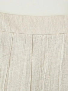 Close-up of the waistband stitching and linen texture on the beige shorts