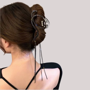 Detail of snake-shaped hair claw with rhinestone tassels on a sleek bun hairstyle