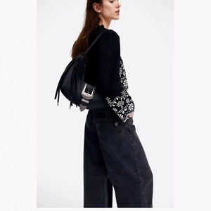 Retro black leather crossbody bag with silver buckle and tassel detail on model