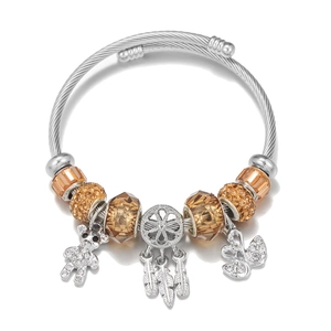 DIY stainless steel cable bracelet with bear and dreamcatcher charms on white background