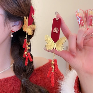 Detailed view of red velvet butterfly hair clips with gold bells and long tassels