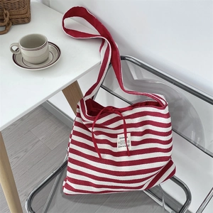 Detail of red and white striped canvas tote bag with drawstring on a stylish chair