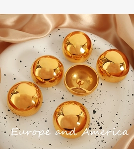 Macro detail of textured golden ball stud earrings on elegant pink silk and tray background