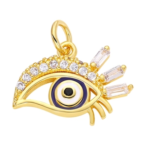 Macro detail of gold-plated evil eye pendant with blue enamel and sparkling zircons