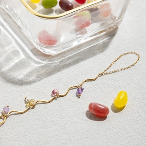 Detailed shot of 18k gold wave bracelet with colorful natural stones and pearls