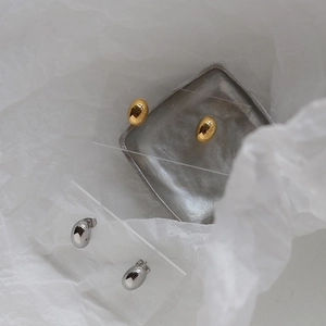Detail shot of oval metallic earrings in gold and silver finish on acrylic stands