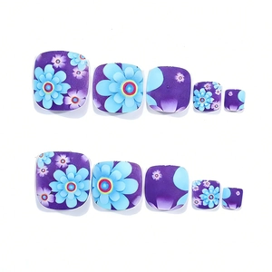 Detailed view of dark purple square press-on toenails with blue floral patterns