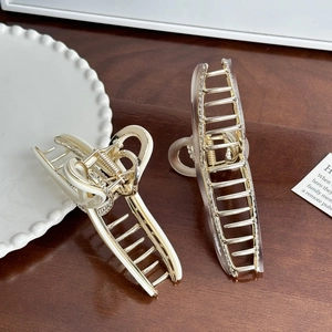 Elegant large gold metal hair claw clips in cream and transparent styles on wood