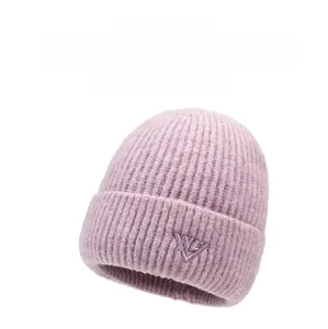 Close-up of thick light pink knit beanie with embroidered letter graphic detailing