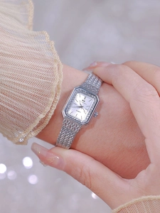 Close-up of luxury rectangular silver watch with crystal bezel and pearl dial on wrist