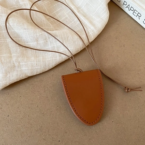 Close-up of brown leather heart pendant necklace with cord on minimalist fabric
