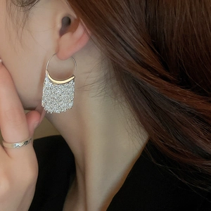 Détail de boucles d'oreilles argentées à pompons en forme de C avec anneau minimaliste assorti