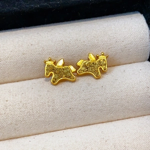 Boucles d'oreilles dorées en forme de cheval avec texture givrée sur un coussin en velours
