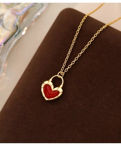 Macro detail of a gold chain necklace with a red heart-shaped locket on a display stand