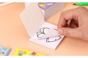Detailed close-up of a hand flipping through a mini cartoon coloring book for kids