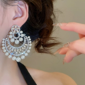 Dettaglio ravvicinato di un orecchino a fiore in argento con perle e strass indossato