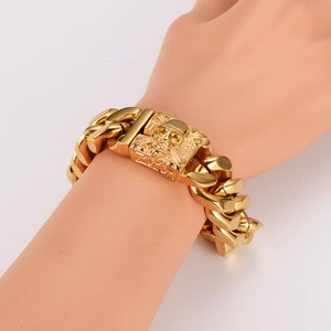 Men's gold stainless steel Cuban link bracelet featuring a detailed skull relief buckle