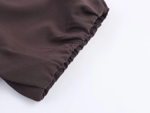 Detail of dark brown blouse featuring puff sleeve elastic cuffs and textured woven fabric