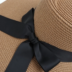 Close-up of brown straw hat weave with elegant black grosgrain ribbon bow detail