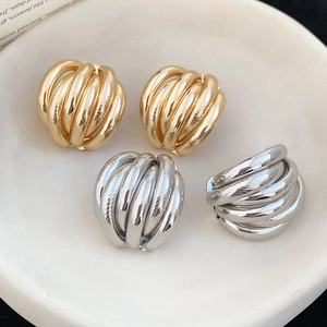 Macro shot of gold and silver dome earrings with multi-layer textured spiral design