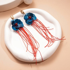 Détail des boucles d'oreilles fleurs en acrylique bleu avec longs pompons rouges