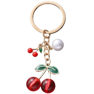 Detailed macro of golden keychain with red cherry charms and white pearl pendant