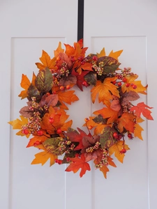 Detailed view of autumn wreath featuring realistic maple leaves and colorful berries