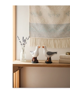 Detail of Nordic resin seagull figurines on rock base with a cozy home background