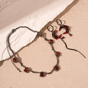 Gothic vintage jewelry set with red gems and black metal tassels on sand texture