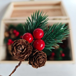 Macro shot of artificial pine needles, red berries and natural cones for DIY decor