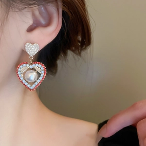 Gros plan de boucles d'oreilles cœur avec perles et cristaux colorés sur un modèle