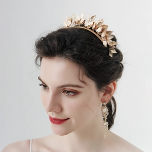 Golden bridal crown with leaf design and matching pearl drop earrings on a model