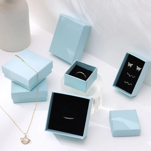 Detail of light blue jewelry boxes showcasing a planet necklace and butterfly earrings