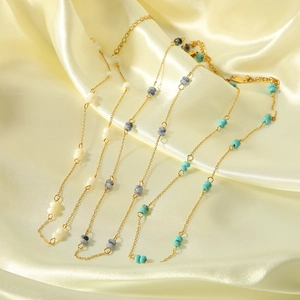 Detail of four handmade beaded stainless steel necklaces on beige silk fabric