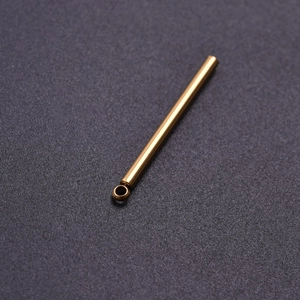 Macro shot of a golden cylindrical 304 stainless steel pendant with a small hanging ring