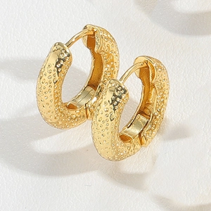 Macro shot of gold hoop earrings featuring a unique hammered grainy texture detail