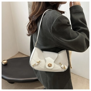 Detail of white baguette bag with vintage gold clasp on shoulder of model in green suit