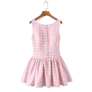 Pink plaid sleeveless dress featuring back buttons and a pleated skirt on a wooden hanger
